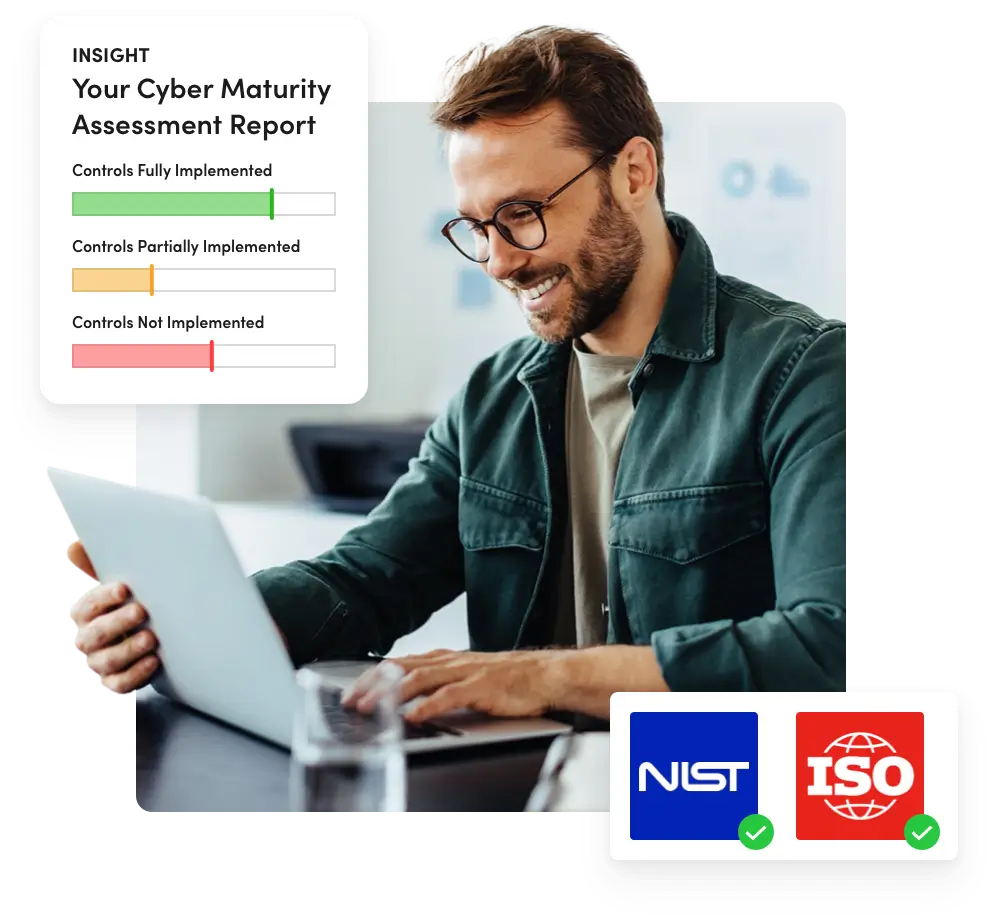 A man using a laptop reviews a Cyber Maturity Assessment report showing controls fully implemented, partially implemented, and not implemented in a color-coded bar chart.